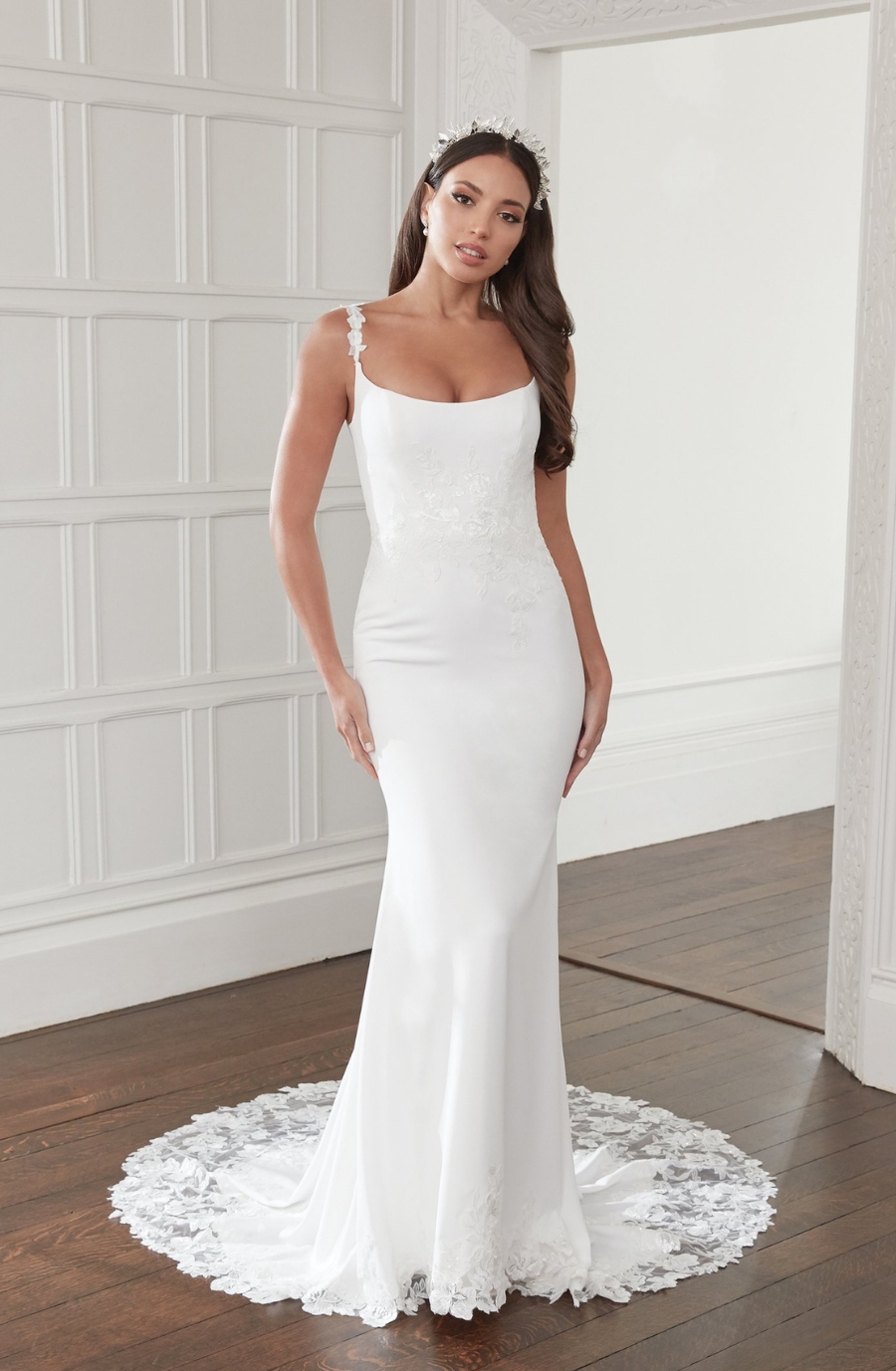 Model is wearing a scoop neck crepe fit and flare wedding dress