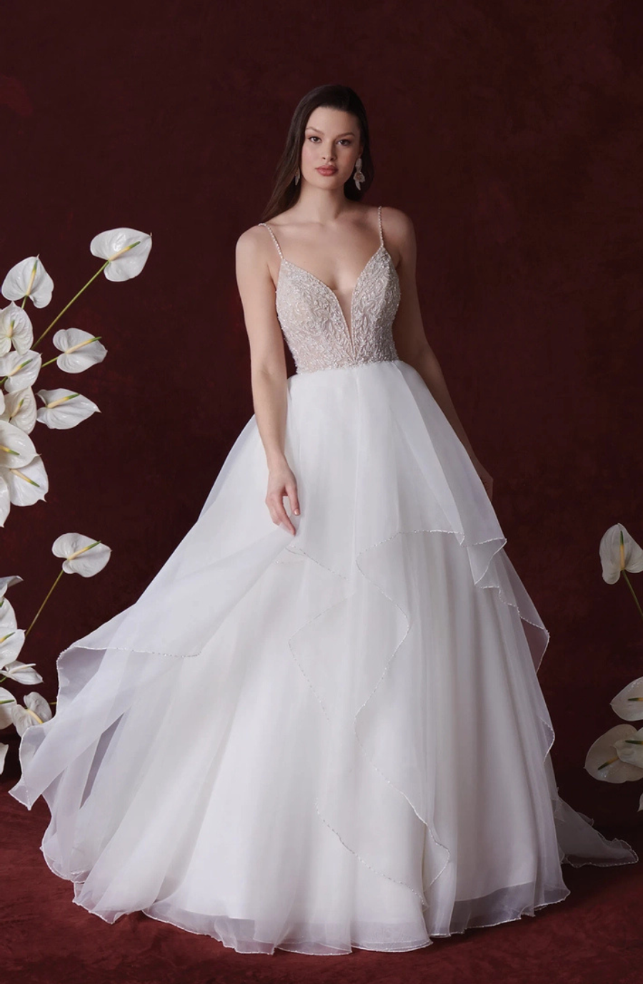 Model is wearing a ball gown wedding dress with a full tulle skirt and delicate spaghetti straps with a beaded bodice
