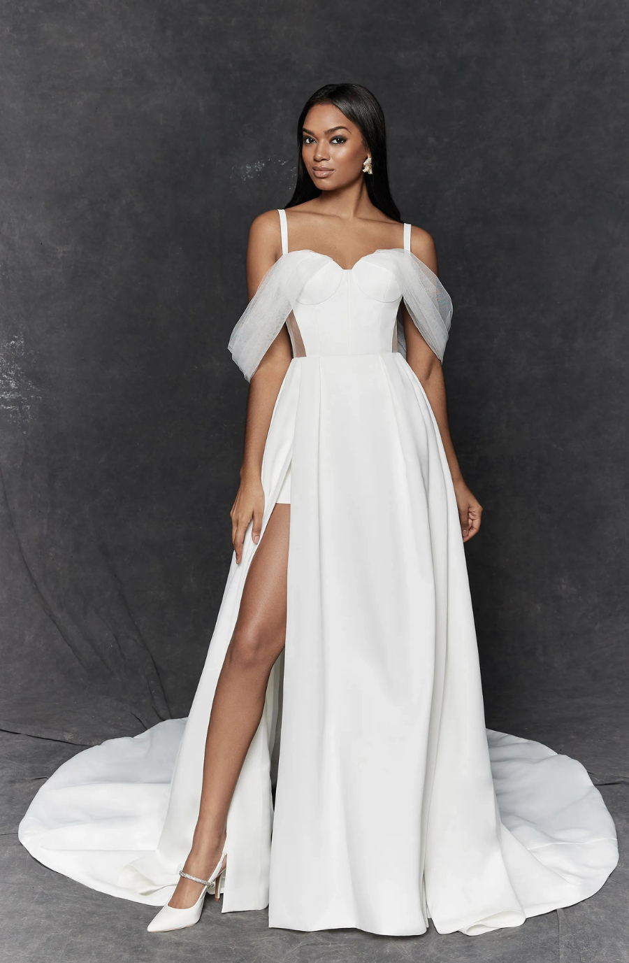 Model is wearing a satin a-line wedding dress with a sweetheart neckline and off the shoulder tulle straps