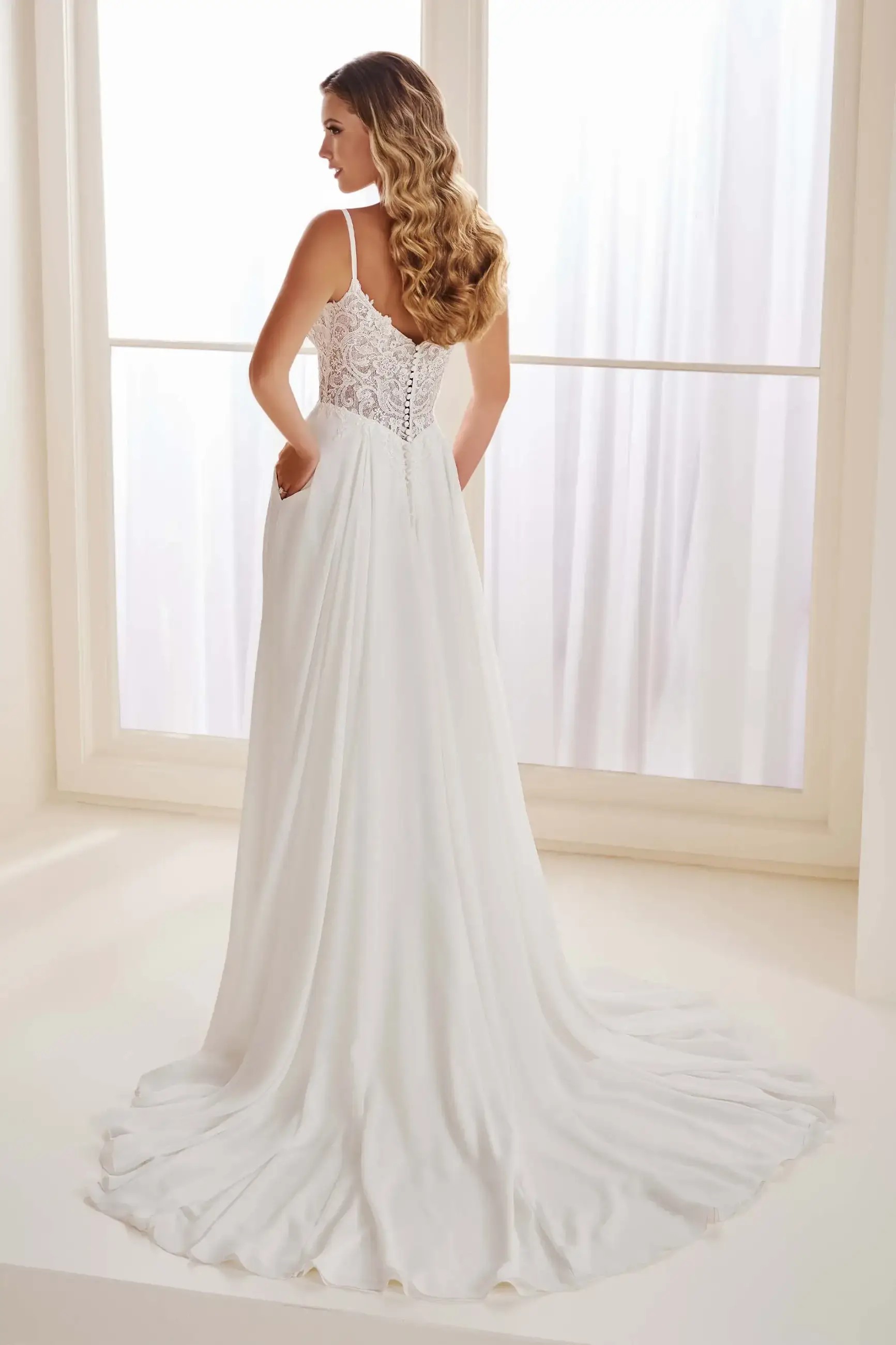 Model is wearing an a-line chiffon wedding dress with delicate spaghetti straps 
