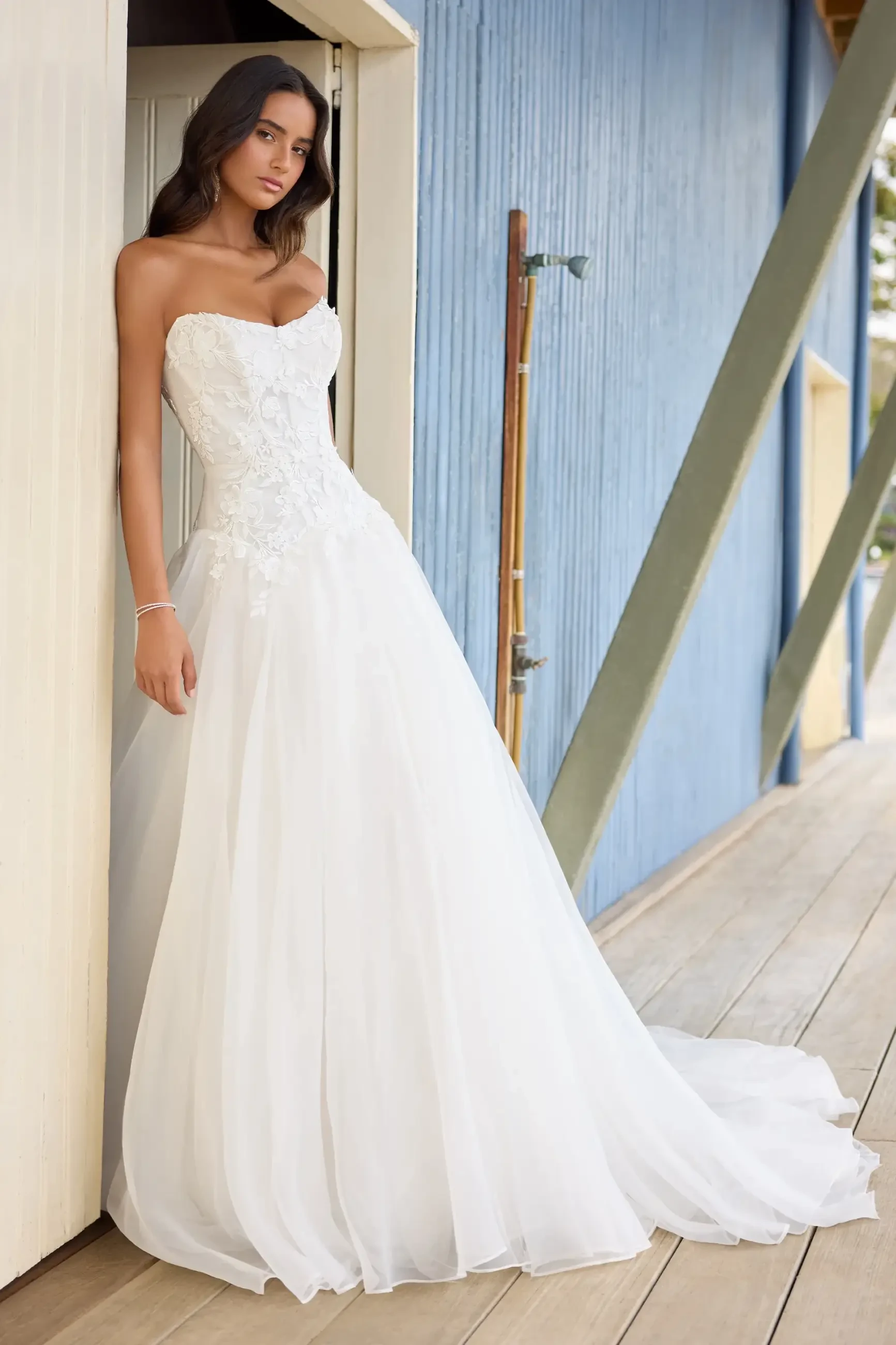 Model is wearing a strapless drop-waist gown with a voluminous organza A-line skirt